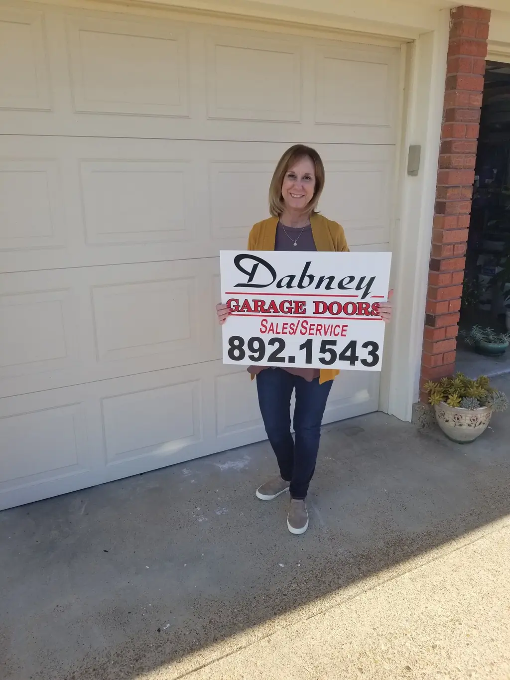 A completed Dabney residential garage door installation with the customer standing in front of it